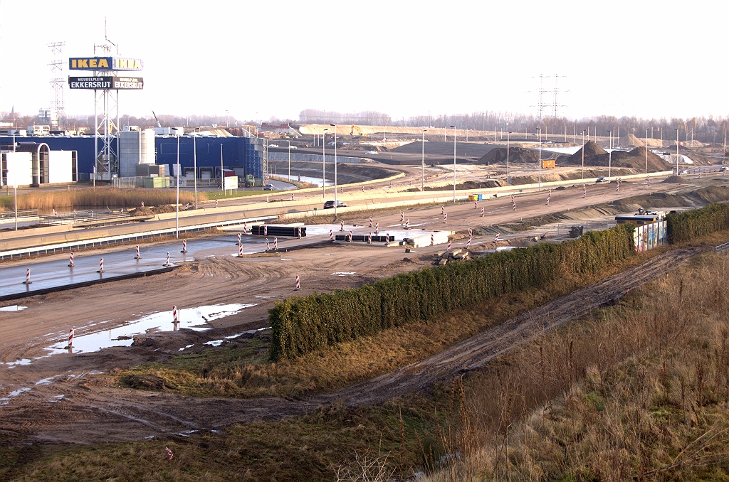 20090124-103344.jpg - In dezelfde nieuwsbrief staat een plaatje van een fasering per april 2009, waar al het verkeer vanuit de richting Tilburg via de af- en toerit van de nieuwe aansluiting Ekkersrijt wordt geleid. Dat lijkt in tegenspraak met de foto, waarin nu juist op de zuidelijke A50 hoofdrijbaan als eerste asfalt is aangebracht. Na KW 45 (fietstunnel) is al een begin van het talud naar KW 44 aangelegd, maar dat lijkt voorbarig omdat bij genoemde fasering de route naar de bestaande A50/A58 kruising gewoon in verkeer blijft.
