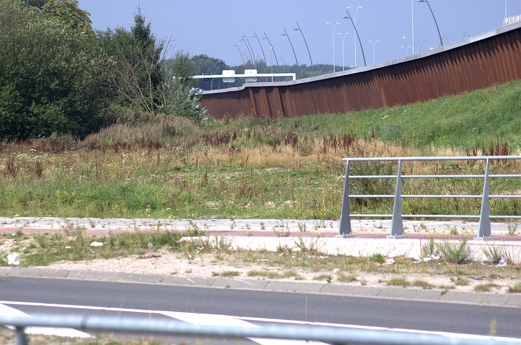 20090816-145658.bmp - Laten we eens kijken hoe de vier armen van de toekomstige Haarlemmermeer-type aansluiting komen te liggen. Aan de noordoost zijde lijkt de situatie eenvoudig, met voldoende ruimte om de afrit vanuit de richting Amsterdam aan te leggen. In het uitstulpsel van het damwanden geluidsscherm is een  voorbereiding voor de afrit  reeds aanwezig in de N2. Zoals in de eerste foto te zien is ligt de Meerenakkerweg verdiept onder KW 14, met brugleuningen tussen rijbanen en fietspaden, die niet verdiept liggen. Het einde van de brugleuning is tevens einde van de verdiepte ligging. Aldus kan de afrit eenvoudig aansluiten op het niet-verdiepte deel van de Meerenakkerweg.