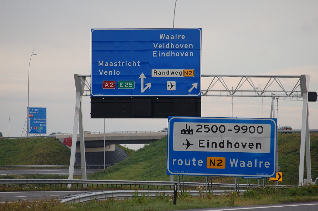 20101031-143531.bmp - Analoog aan de situatie in kp. Ekkersweijer op de A50 vanuit de richting Nijmegen, komt aldus op de A58 vanuit de richting Tilburg de "Randweg N2" weer terug bij het tweede beslismoment. Wijzigingen aan dit portaalbord zijn het afdekken van "-Centrum" onder "Eindhoven" en het toevoegen van het vliegveldpictogram, waardoor in combinatie met het servicebord die bestemming dubbel is bewegwijzerd.  week 200939 
